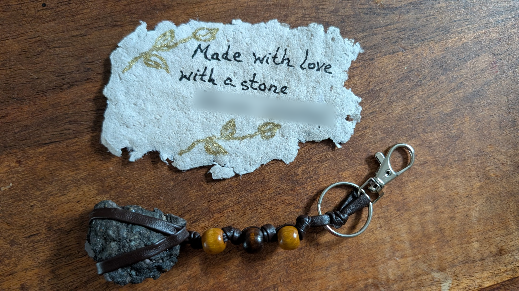 A stone collected on a family outing, wrapped and made into a beaded key chain beside a handwritten tag; the final line is obscured