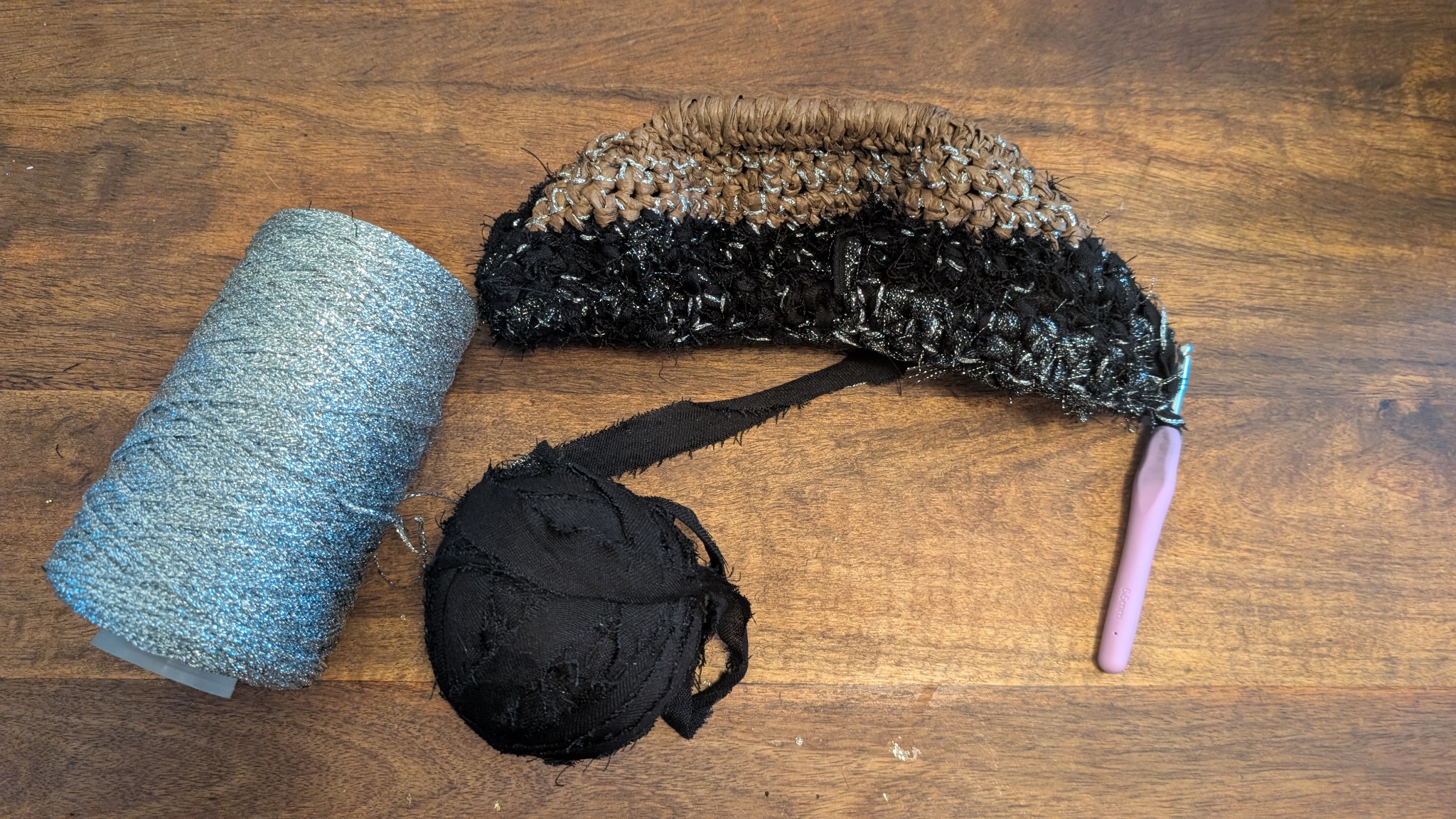 The bag taking shape by crochet beside the old hijab yarn, raffia and silver metallic yarn