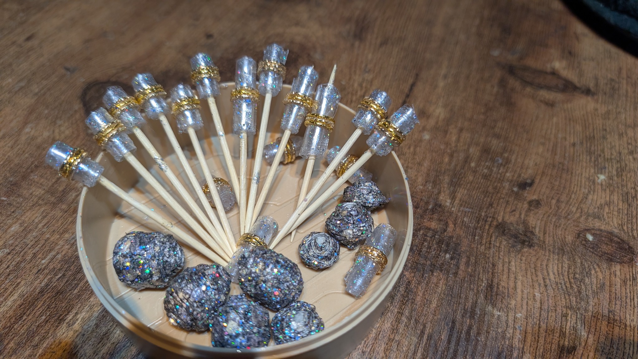 A collection of handmade recycled water-bottle beads displayed on making sticks