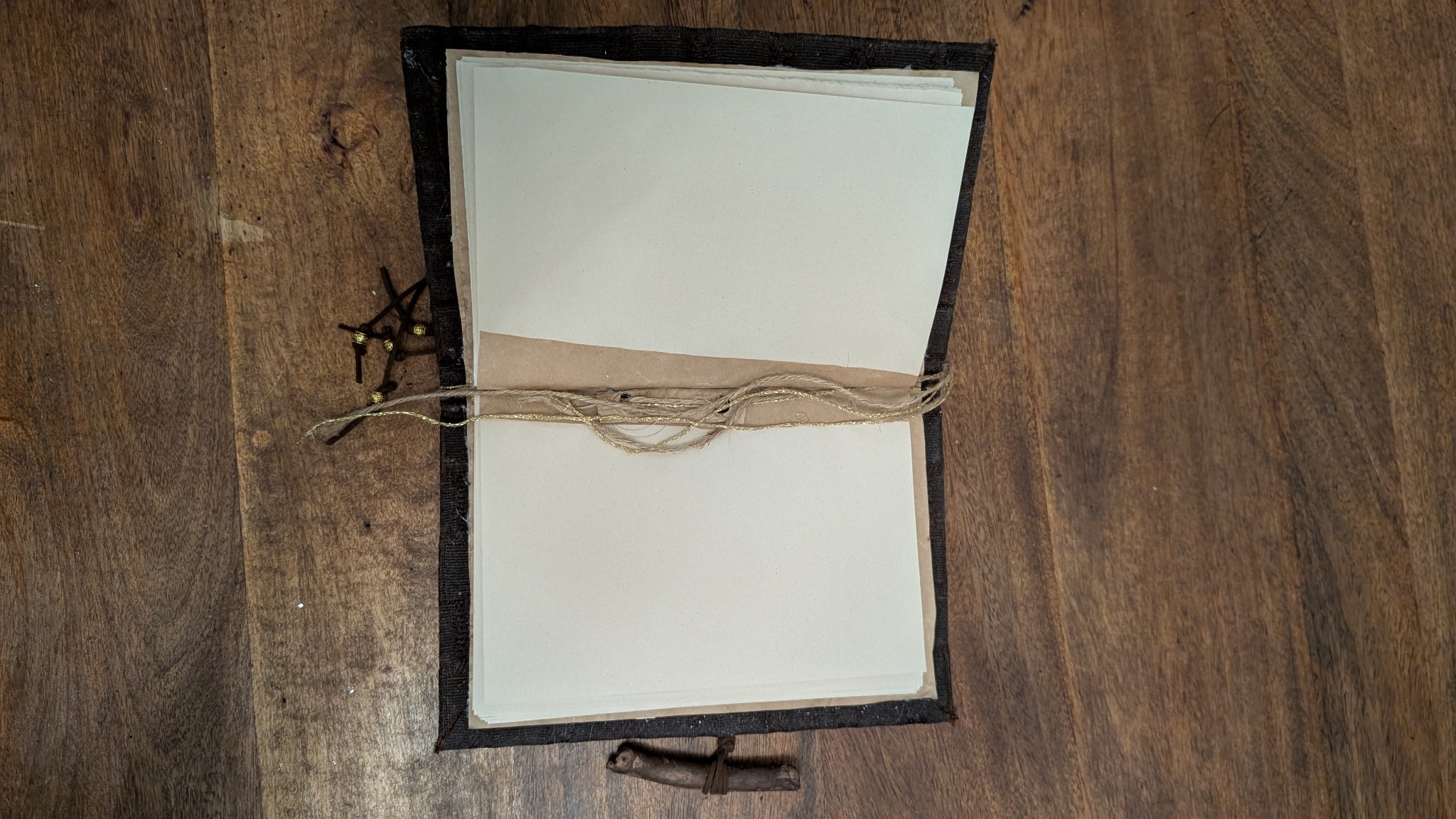 The refillable notebook opened to show its recycled-paper pages and tie closure