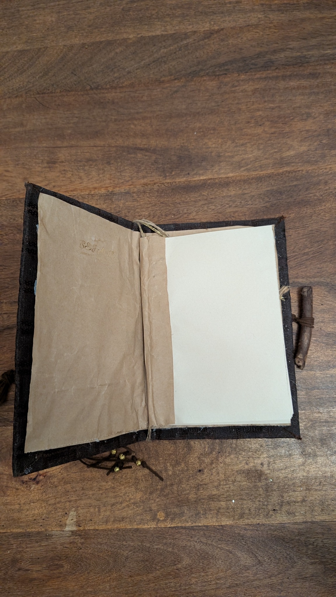 The notebook opened to reveal its envelope lining, removable recycled-paper pages and twig closure
